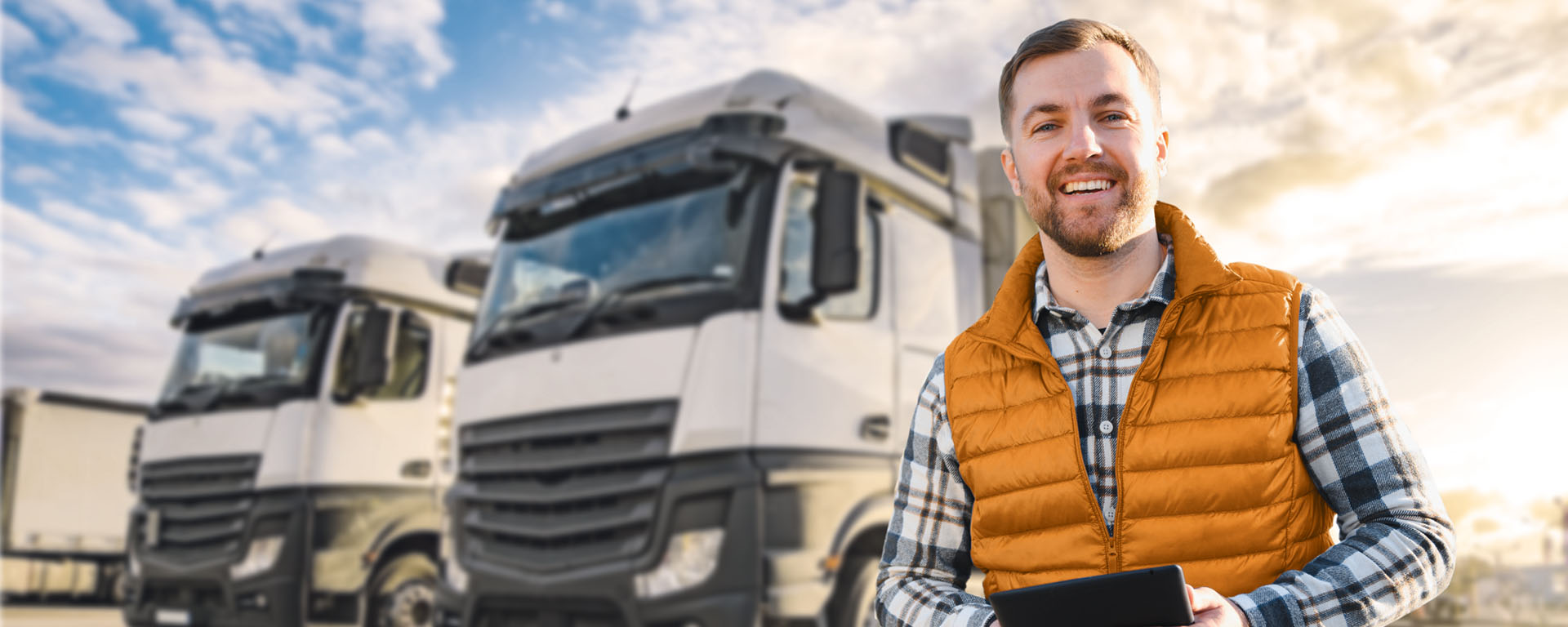 Mann steht vor einer Reihe Lastkraftwagen