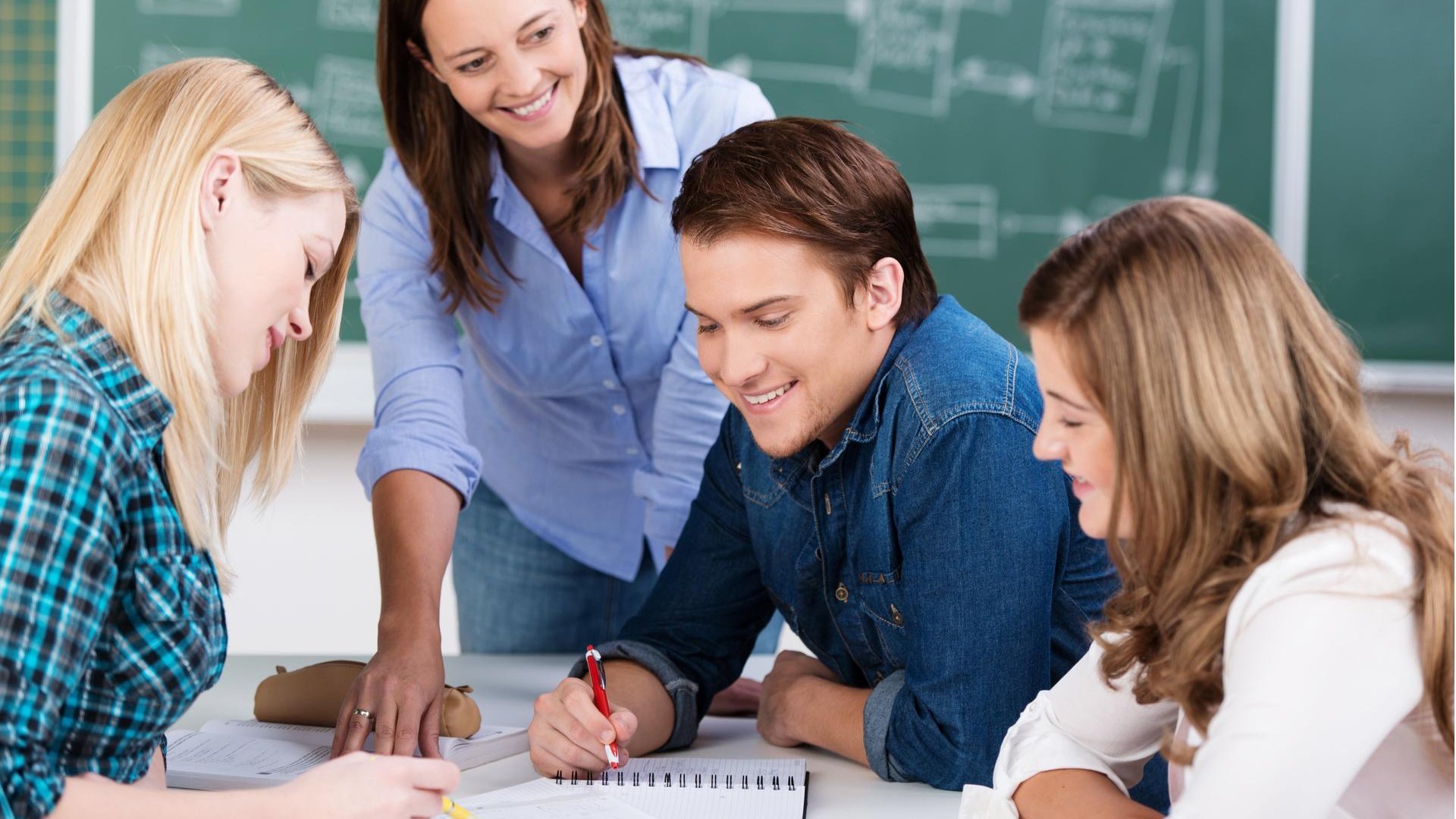 eine Lehrkraft erklärt Schüler*innen eine Aufgabe