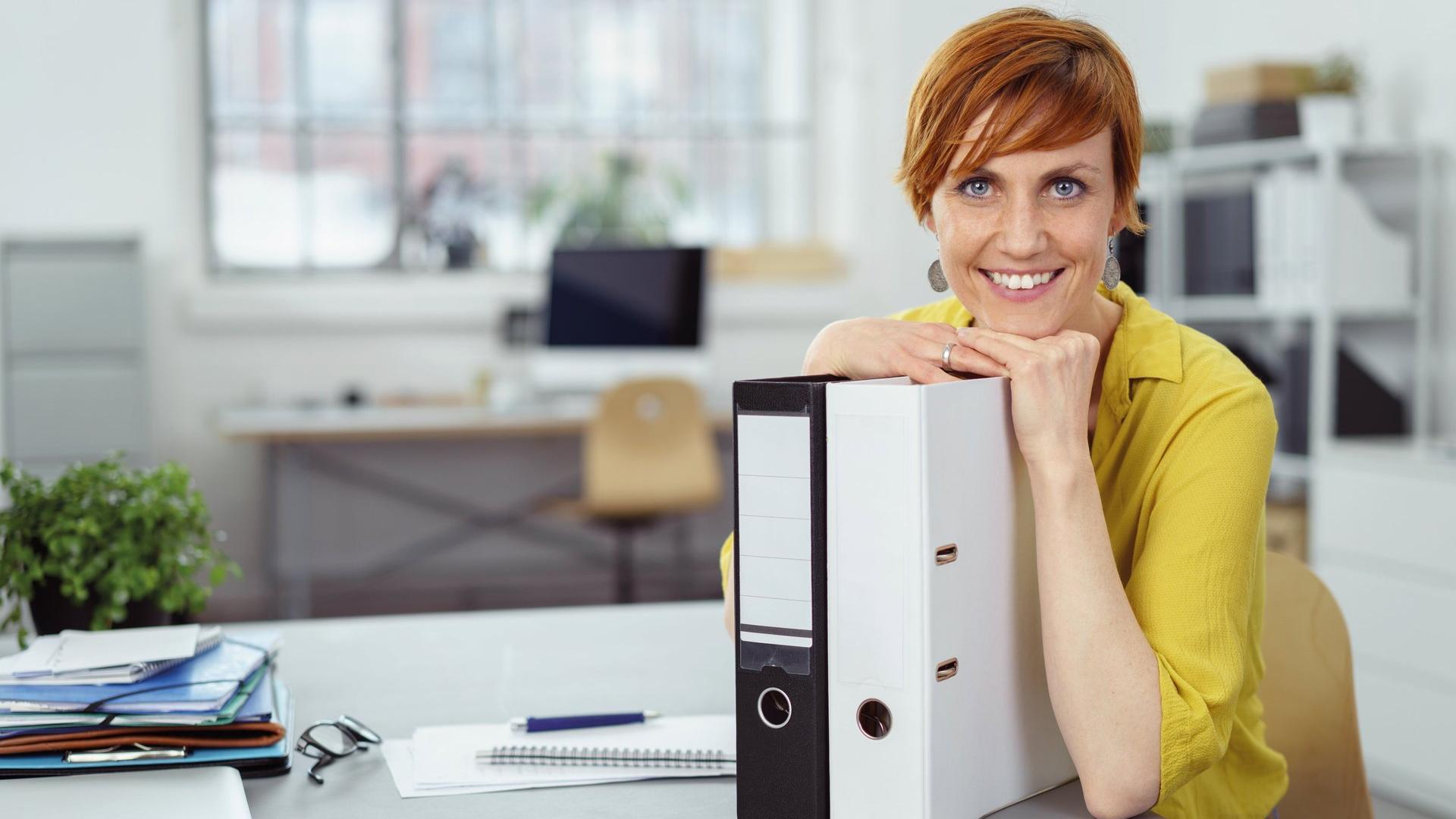 Frau am Schreibtisch mit Aktenordnern