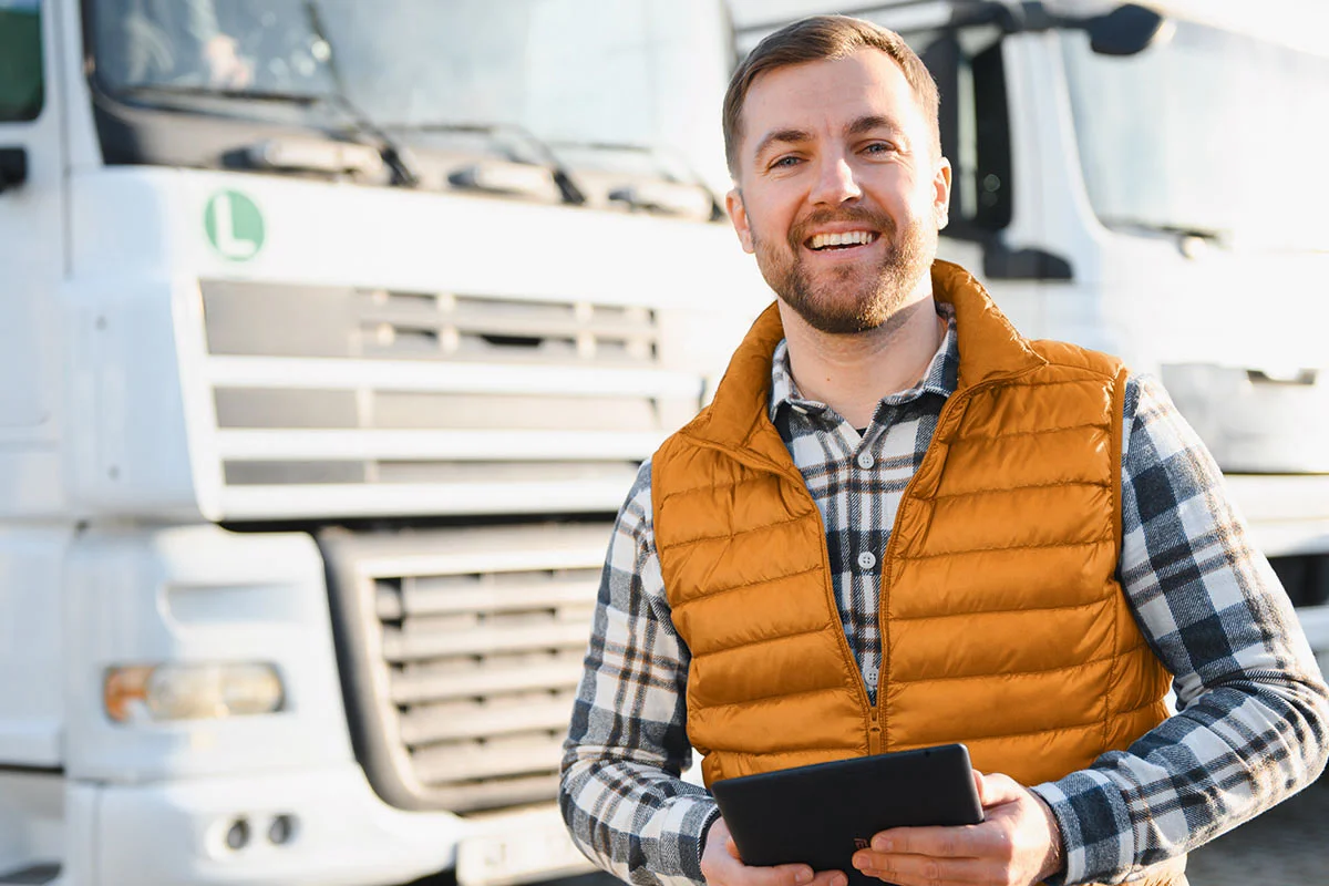 Mann Tablet in der Hand steht vor einem LKW-Fuhrpark