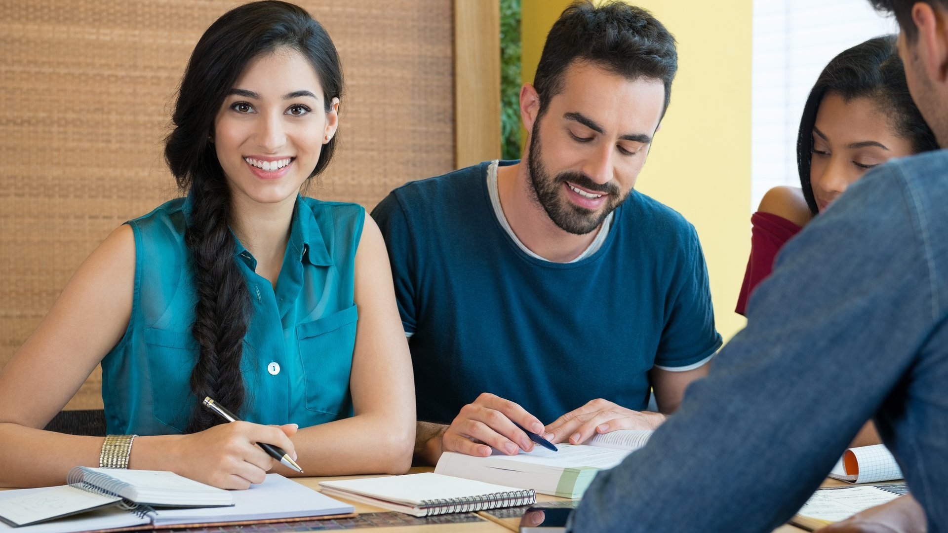 Junge Frau am Tisch blickt in die Kamera